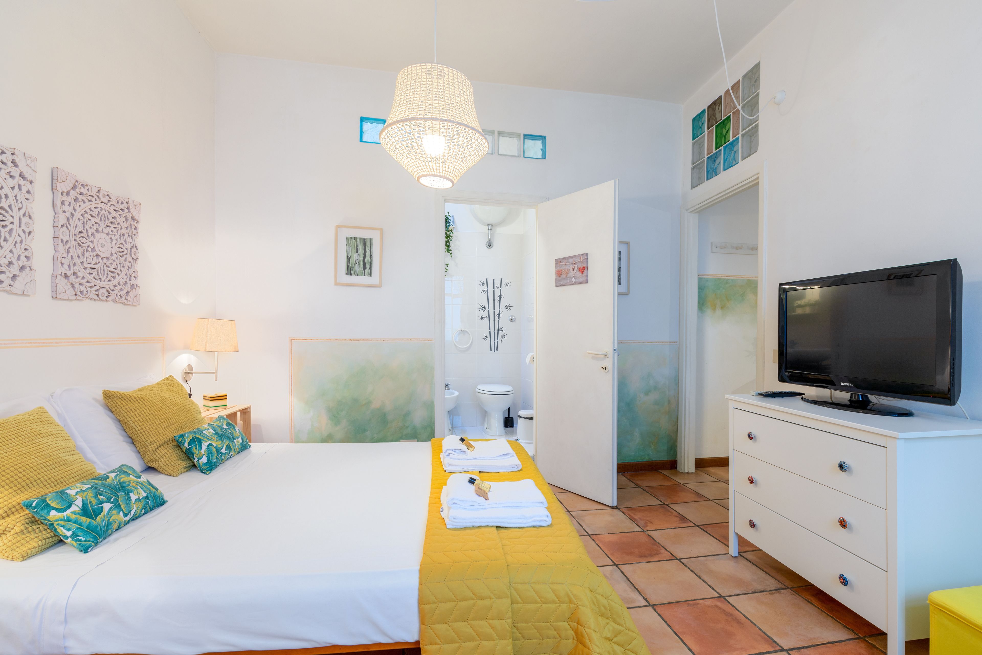 A hotel room with a bed, a television, a bathroom, and a hallway.