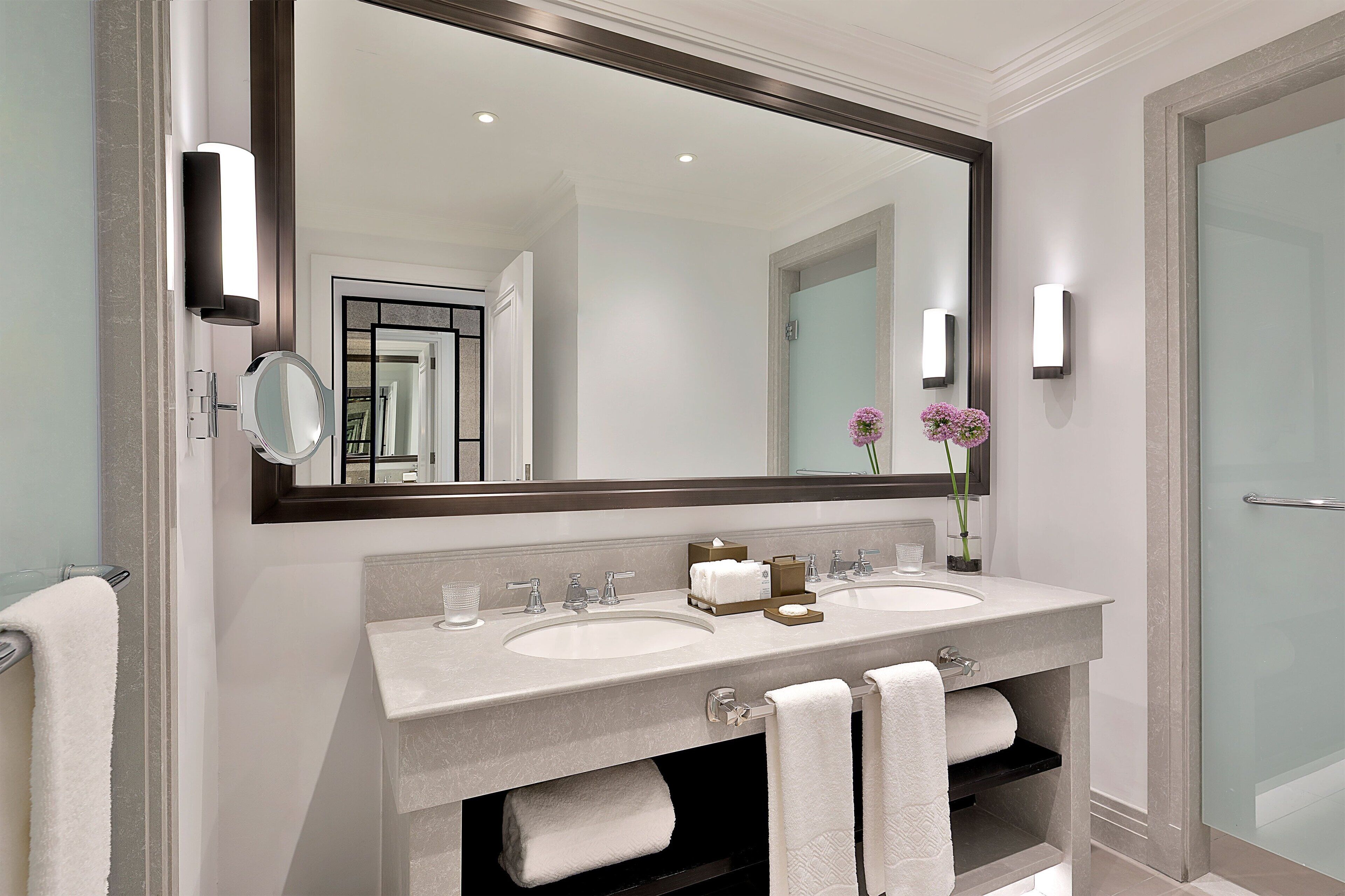 Un baño moderno con dos lavamanos, un espejo grande y una cabina de ducha de vidrio.
