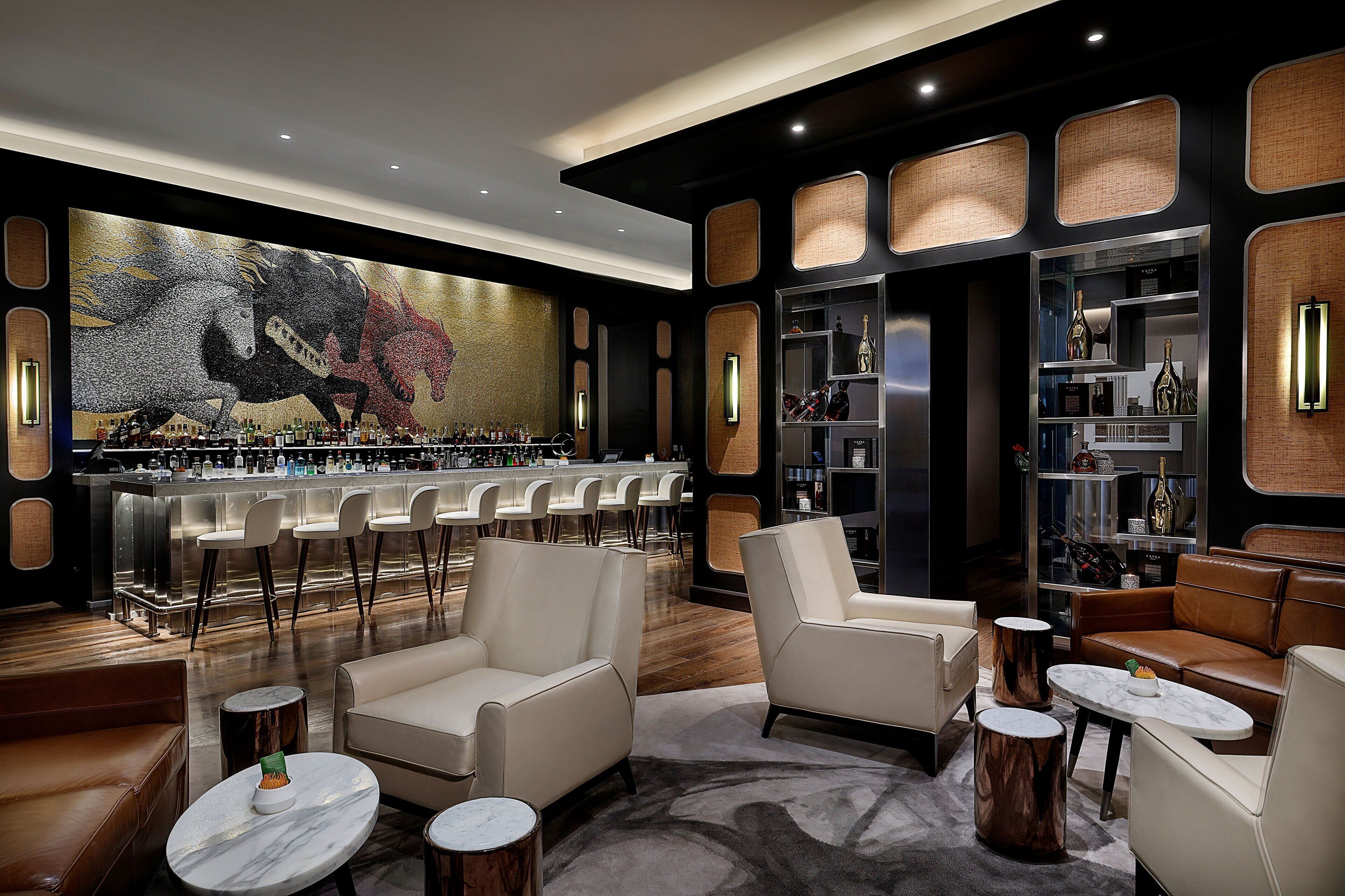 Zona de bar moderna con una barra larga, varios taburetes y un gran mural de caballos.
