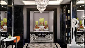 A modern lobby with a chandelier, a reception desk, and a patterned floor.