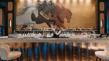 A bar area with a bartender, a large horse mural, and a variety of liquor bottles.