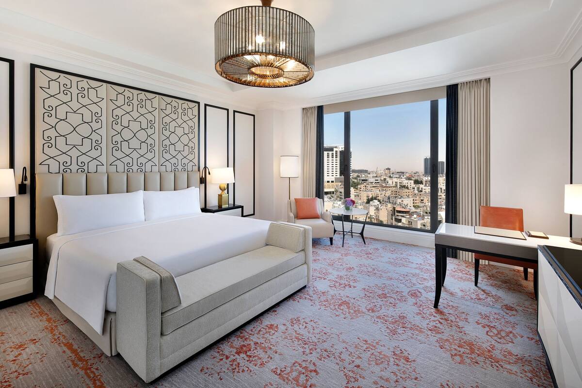 A hotel room with a large bed, a sofa, a desk, and a view of the city.