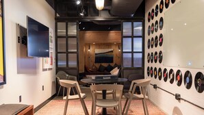 A room with a round table, four chairs, a flat-screen TV, and a wall of vinyl records.