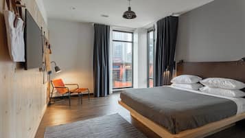 A modern bedroom with a wooden bed, a chair, a desk, and a large window with curtains.