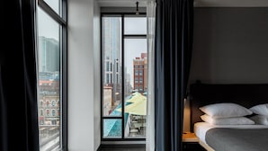 Camera d'albergo con un'ampia finestra, un letto e vista sulla città.