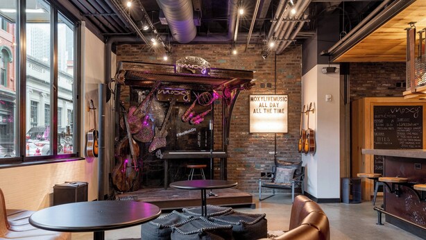 A cozy music venue with a stage, seating area, and a chalkboard menu.