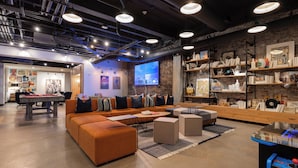 Un'area lounge moderna con un grande divano arancione, un tavolino e una libreria.