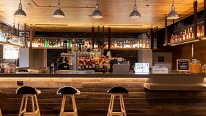 A bar area with wooden stools, a bar counter, and various bottles of liquor.