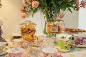 A table set with floral-patterned tea cups, saucers, and a variety of pastries and desserts. - Hotel Ristorante Alla Vittoria (Solferino)