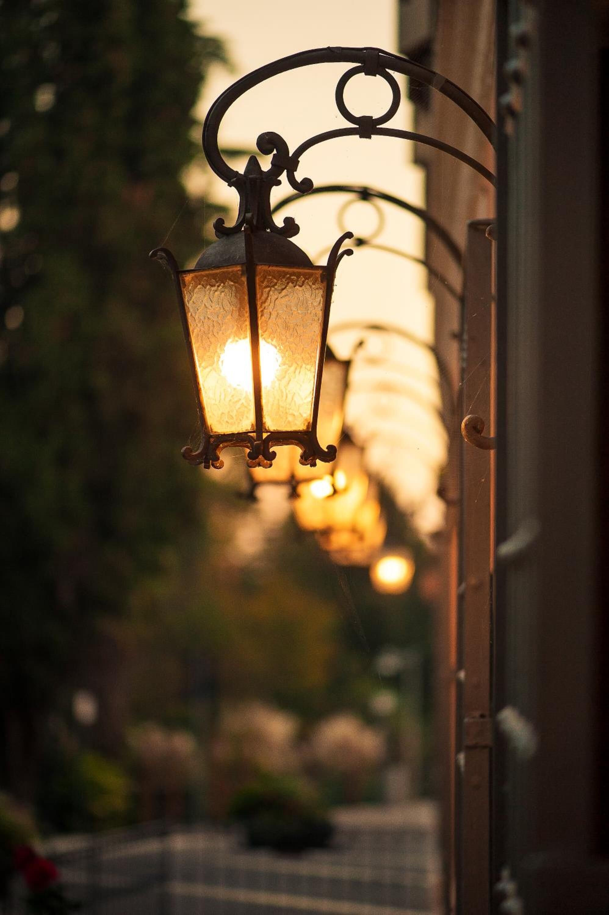A row of hanging lanterns with a warm glow, attached to a metal structure.
