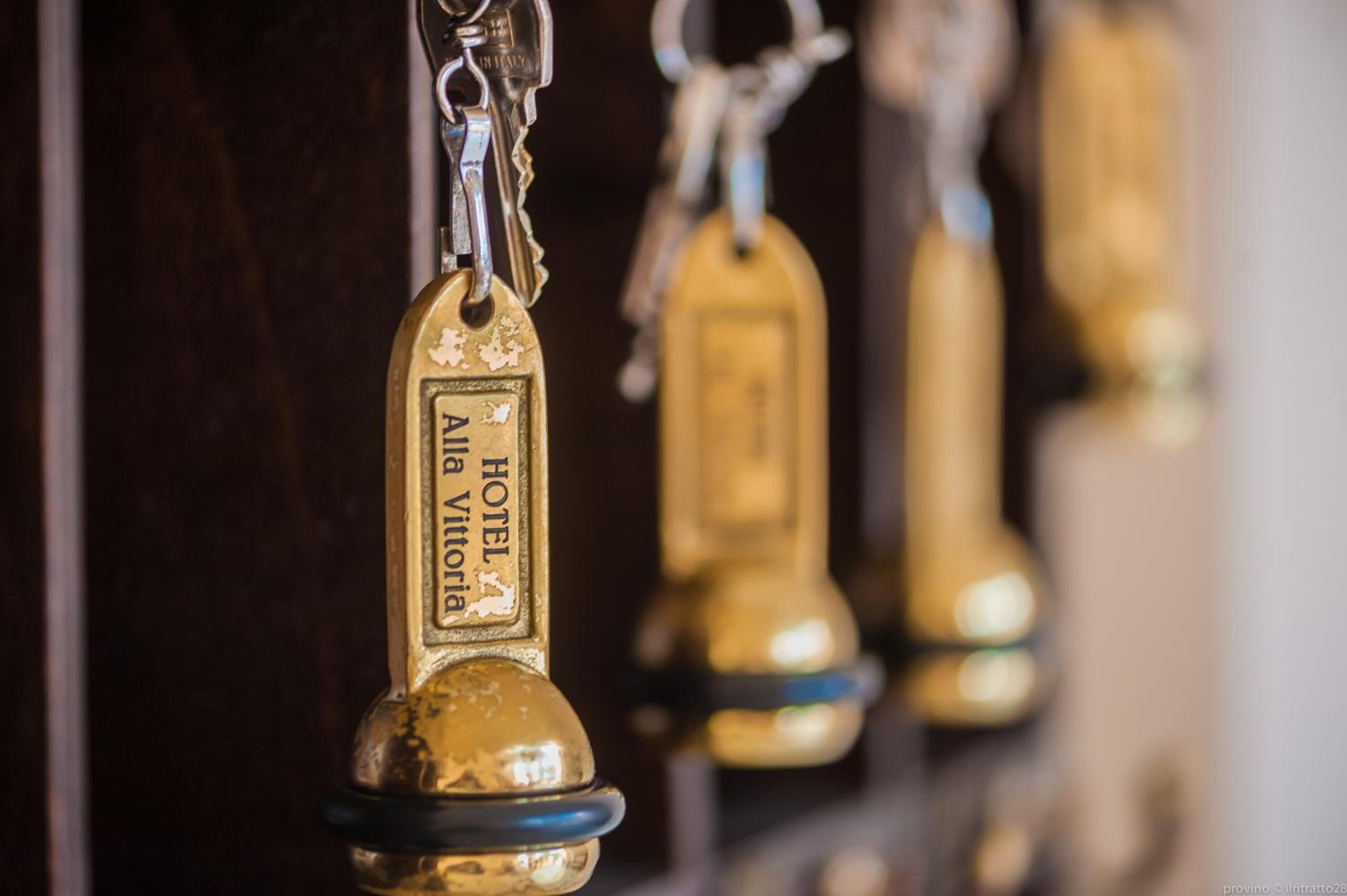 Eine Reihe goldener Schlüsselanhänger mit dem Schriftzug 'HOTEL Vitoria'.