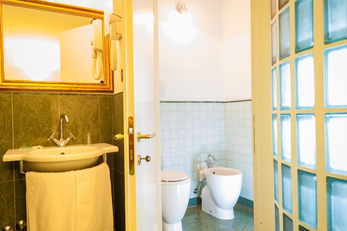 A bathroom with a sink, toilet, bidet, and a mirror.