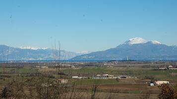 Un paysage rural avec une montagne en arrière-plan, des champs et quelques bâtiments.