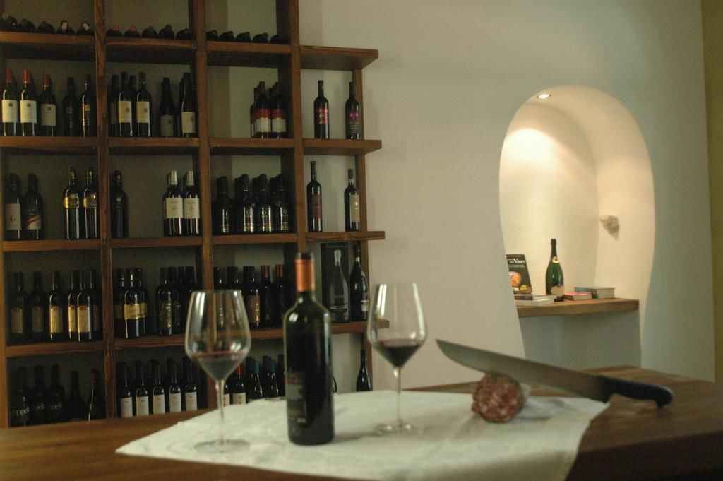 Una bodega con estantes llenos de botellas de vino y dos copas sobre una mesa.