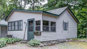 A log cabin with a green door, windows, and a small porch area.