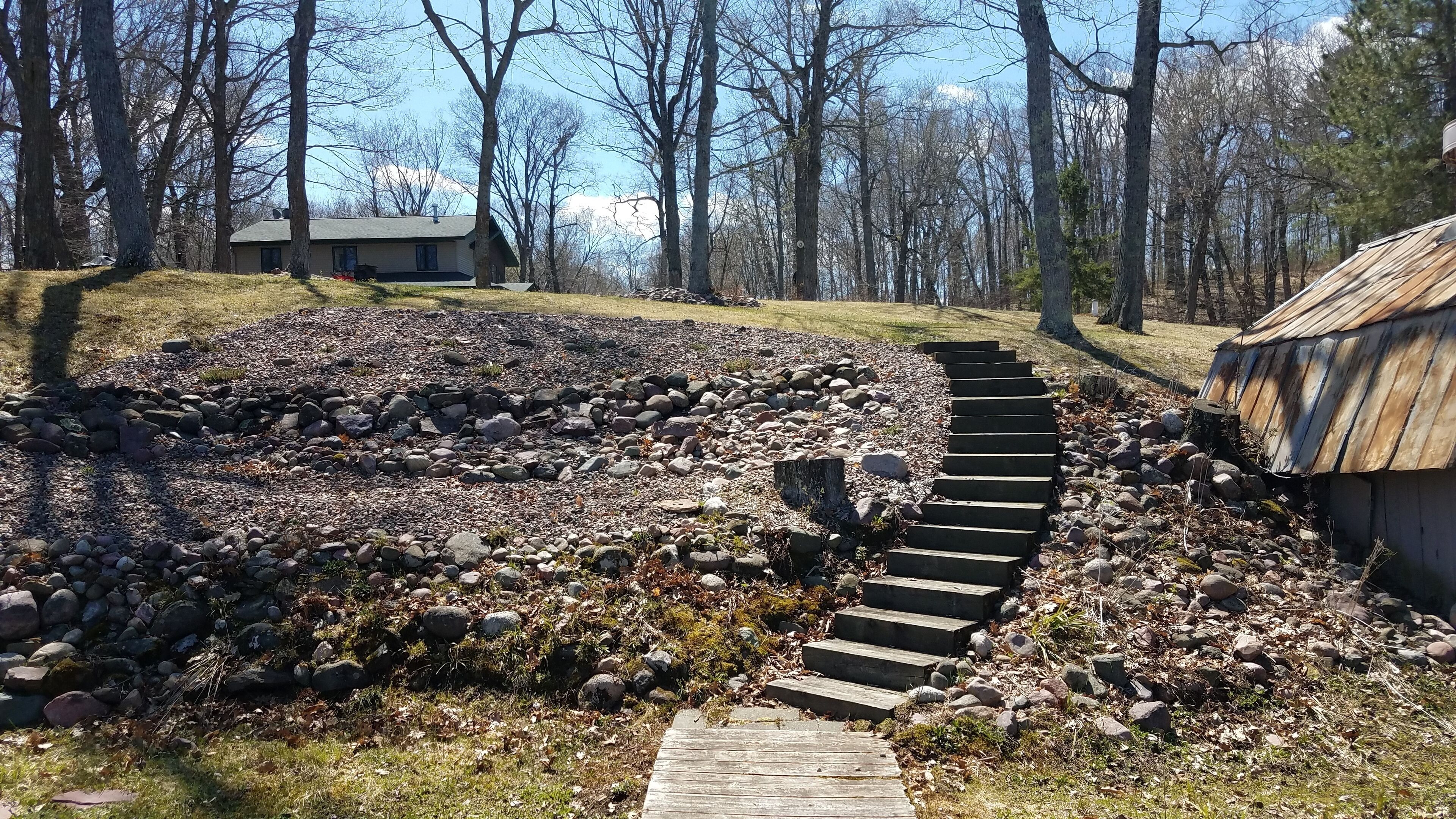 A stone pathway leading to a rustic cabin surrounded by a forest.