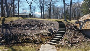 A stone pathway leading to a rustic cabin surrounded by a forest.