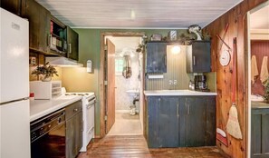 Kitchen with central island, sink, and stove, featuring wooden cabinets and a refrigerator.