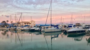 A marina with multiple boats docked, a building with arches, and palm trees in the background. - Residencial Duquesa 2239 Sea & Sun (Manilva)