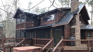 Une cabane à deux étages dotée d’une terrasse, d’un jacuzzi et d’une cheminée.