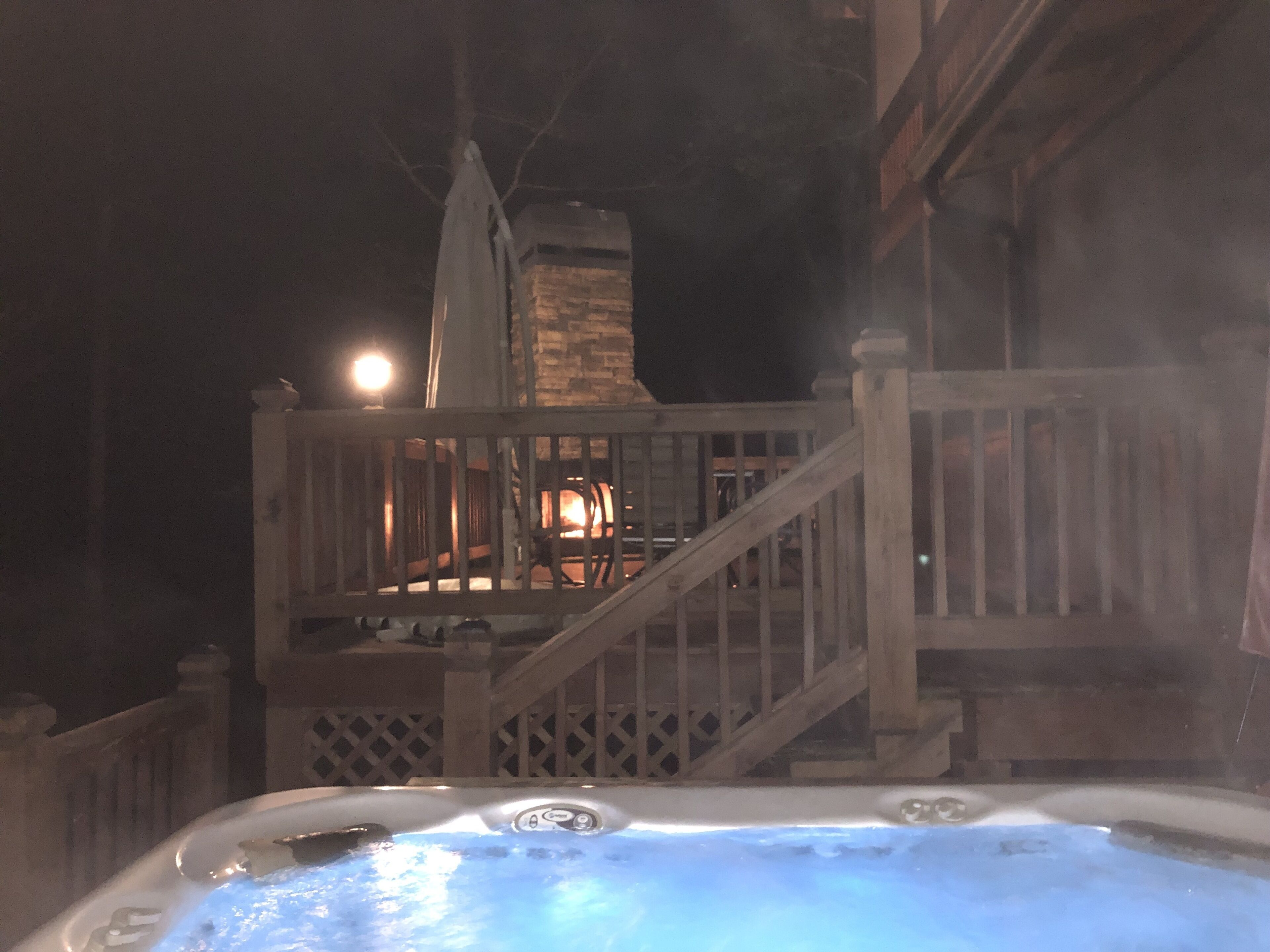 Ein Whirlpool mit einer Holzterrasse und einer Steinsäule im Hintergrund.