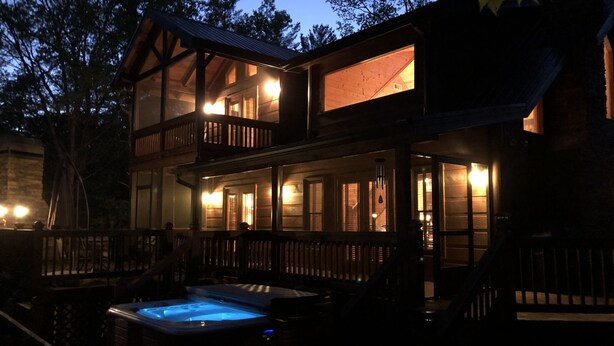 Une cabane en bois à deux étages, dotée d’un bain à remous et d’un balcon.