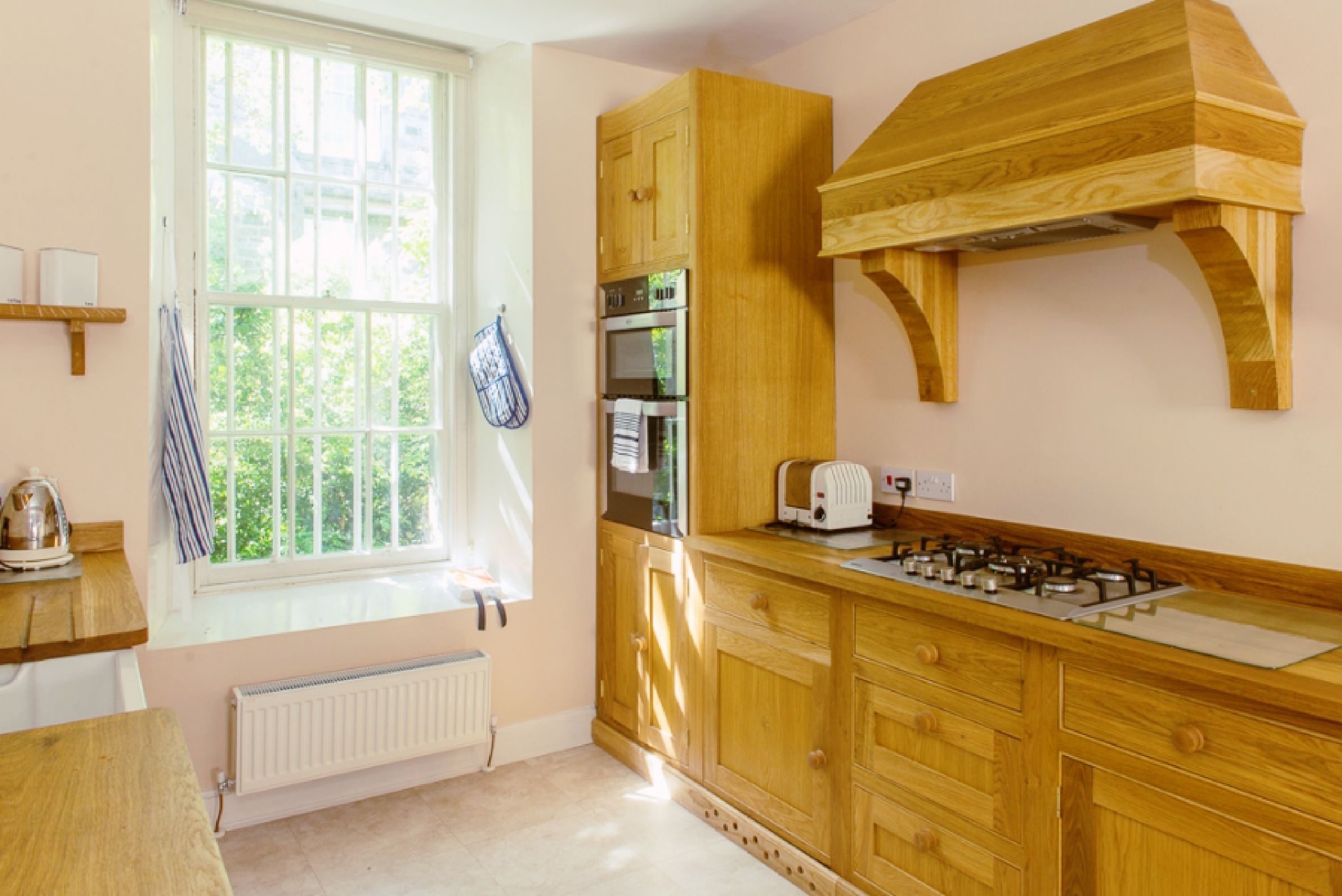 A kitchen with wooden cabinets, a window with a towel hanging, a gas stove, and a built-in oven.
