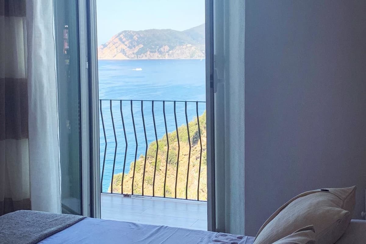 Un dormitorio con cama, vistas al mar y un balcón con barandilla.