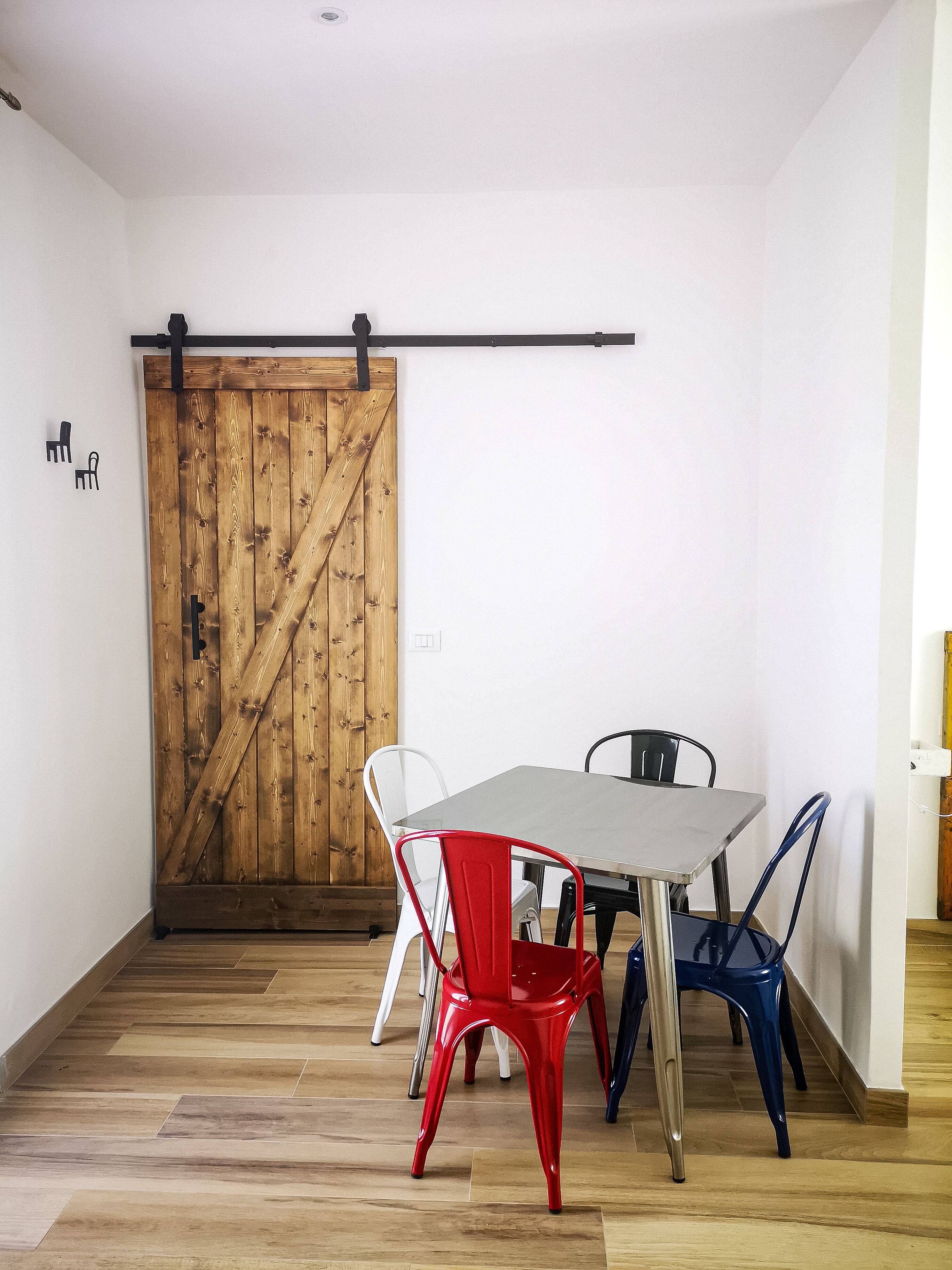 A dining area with a wooden barn door, a metal sliding barn door, and a table with four chairs.