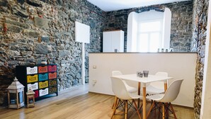 A room with a stone wall, a white cabinet, a white table with chairs, and a wooden floor. - Punto Zero (Vernazza)