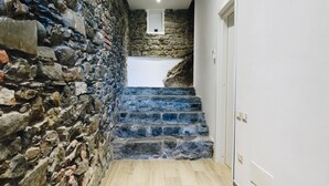 A stone staircase leading to a landing with a white wall and a door. - Punto Zero (Vernazza)