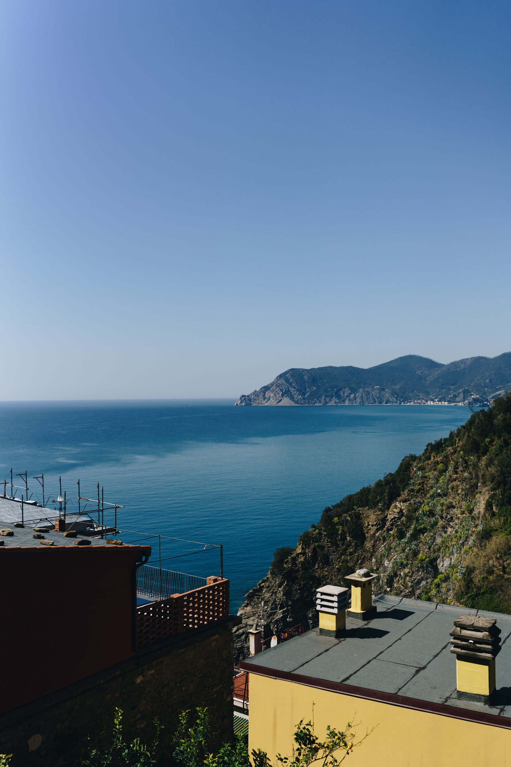 Eine Küstenansicht mit blauem Himmel, ruhiger See und einem felsigen Hang.