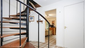A spiral staircase with wooden steps and black metal railings leading to a room with a checkered floor. - Central New Town Apartment (Edinburgh)
