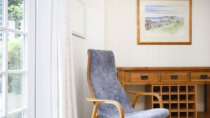 A room with a window, a chair, a wooden cabinet with drawers, and a framed painting on the wall. - Central New Town Apartment (Edinburgh)