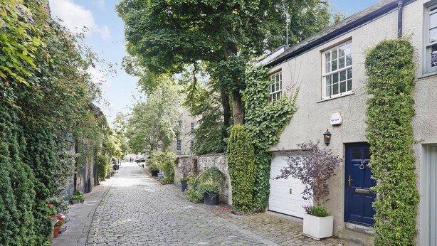A cobblestone street lined with ivy-covered buildings, a blue door, and a white garage door. - Central New Town Apartment (Edinburgh)