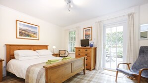 A bedroom with a wooden bed, a desk with a computer, a chair, and a view of the outdoors through a window. - Central New Town Apartment (Edinburgh)
