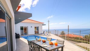 A modern outdoor dining area with a pool, a table set for breakfast, and a view of the ocean. - CalhetaScape by Our Madeira (Calheta)