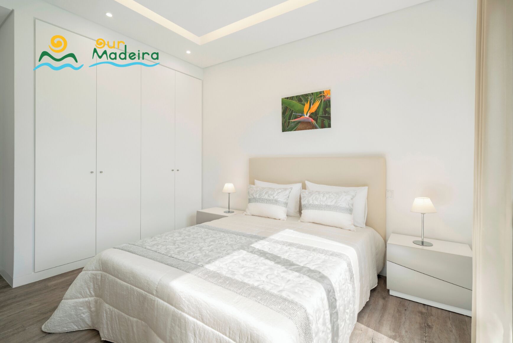 A bedroom with a bed, nightstands, a wardrobe, and a painting on the wall.