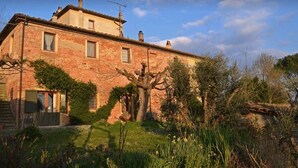 Une maison à deux étages, construite en briques, avec un jardin à l’avant.