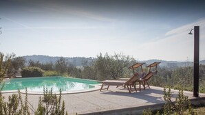 Une piscine dotée de chaises longues et offrant une vue sur le paysage environnant.