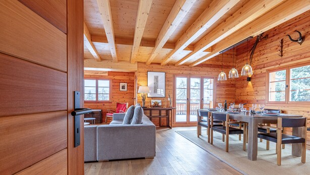 Un intérieur de chalet en bois spacieux, comprenant un coin repas, un canapé et une cheminée.