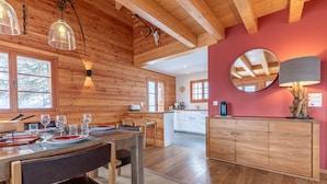 Un intérieur en bois comprenant un coin repas, une cuisine et un mur d’accent de couleur rouge.