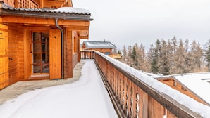 Une cabane en bois dotée d’un balcon enneigé et offrant une vue sur les arbres.