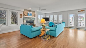 Un salon spacieux avec une cheminée en pierre, des canapés de couleur turquoise et un téléviseur.