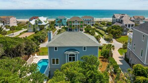 Un quartier résidentiel en bord de mer, avec des maisons, une piscine et une plage en arrière-plan.