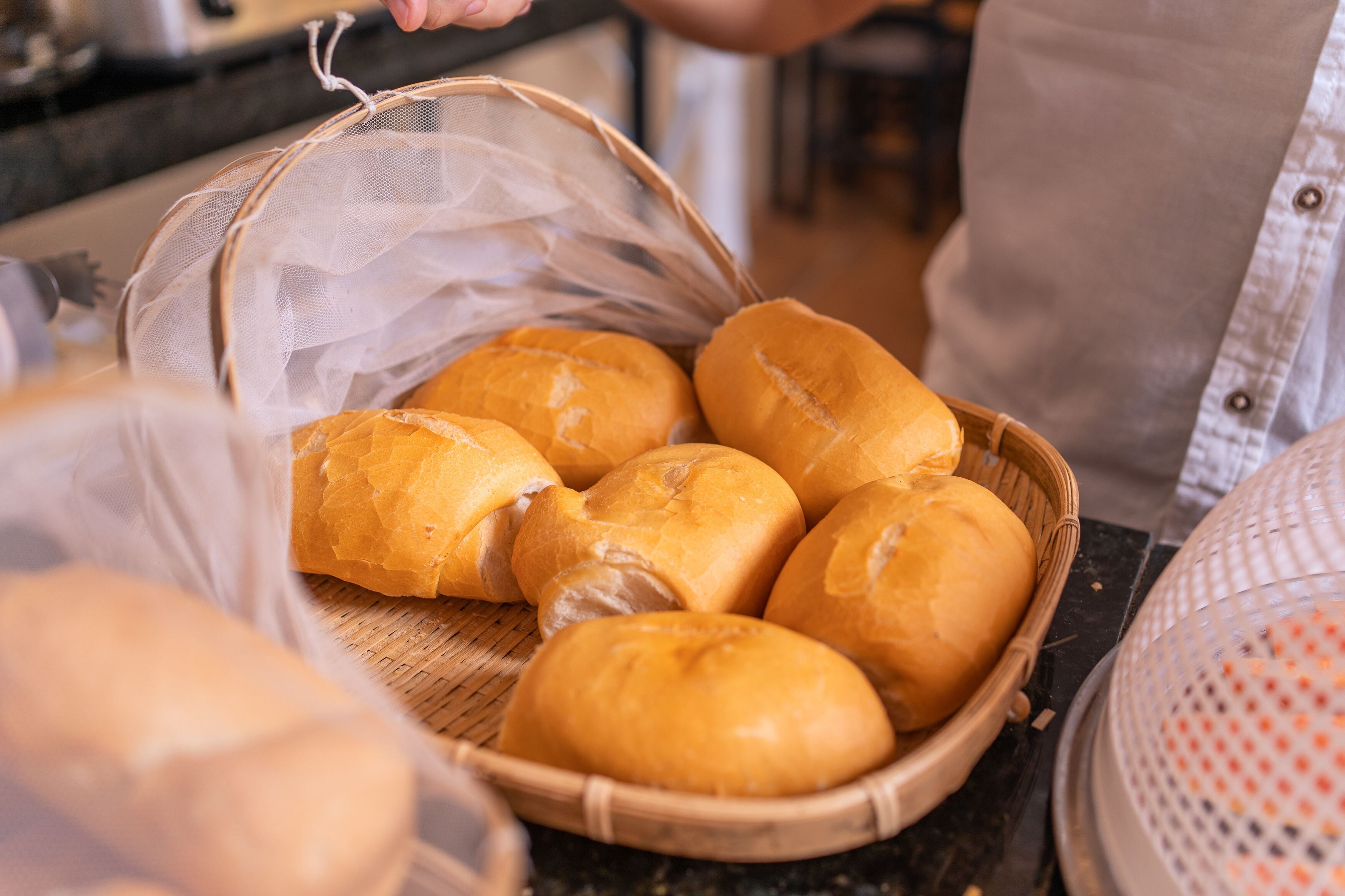 A basket of freshly baked bread rolls on a kitchen counter.