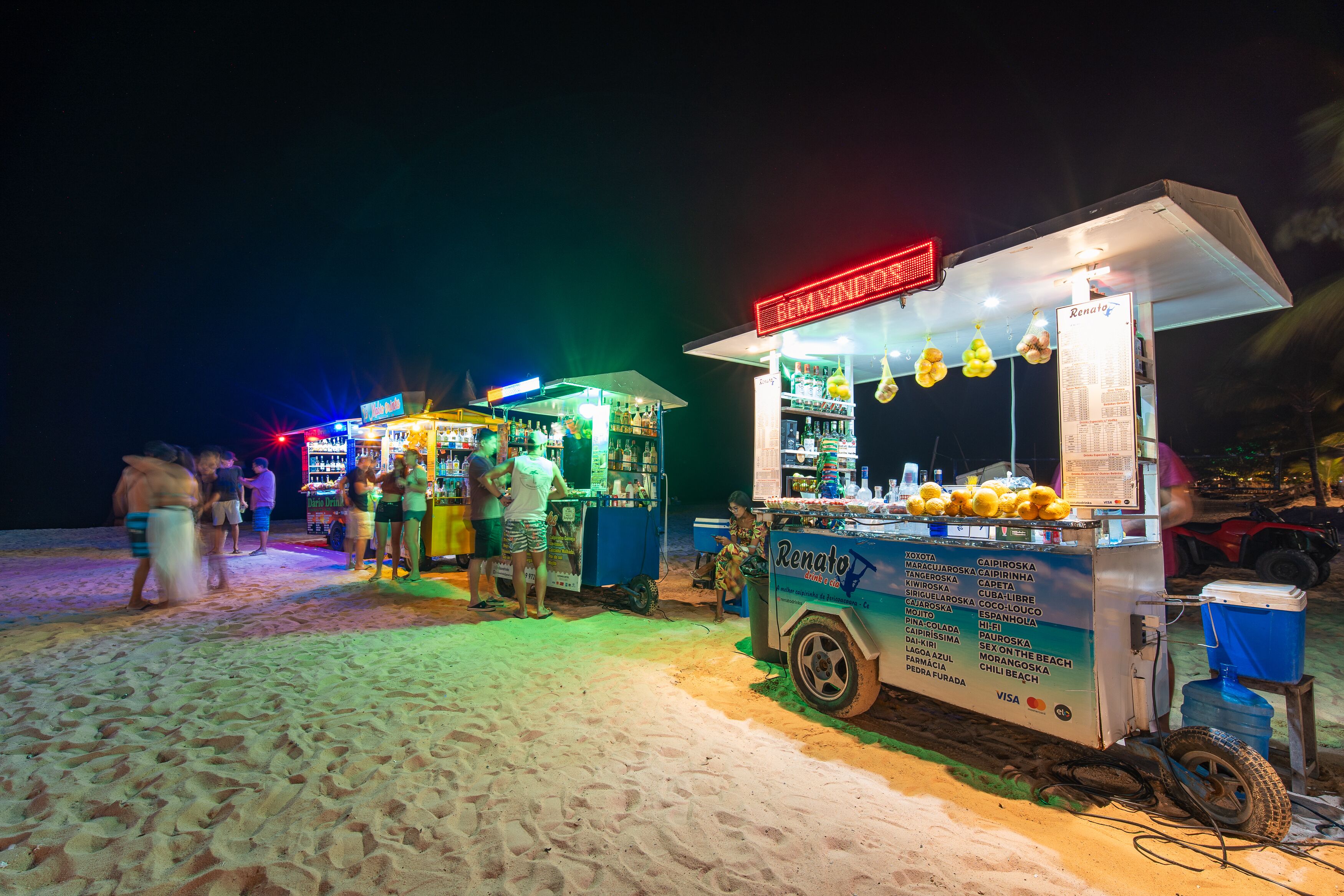 Ein Imbisswagen am Strand mit Speisekarte und Kühlbox.