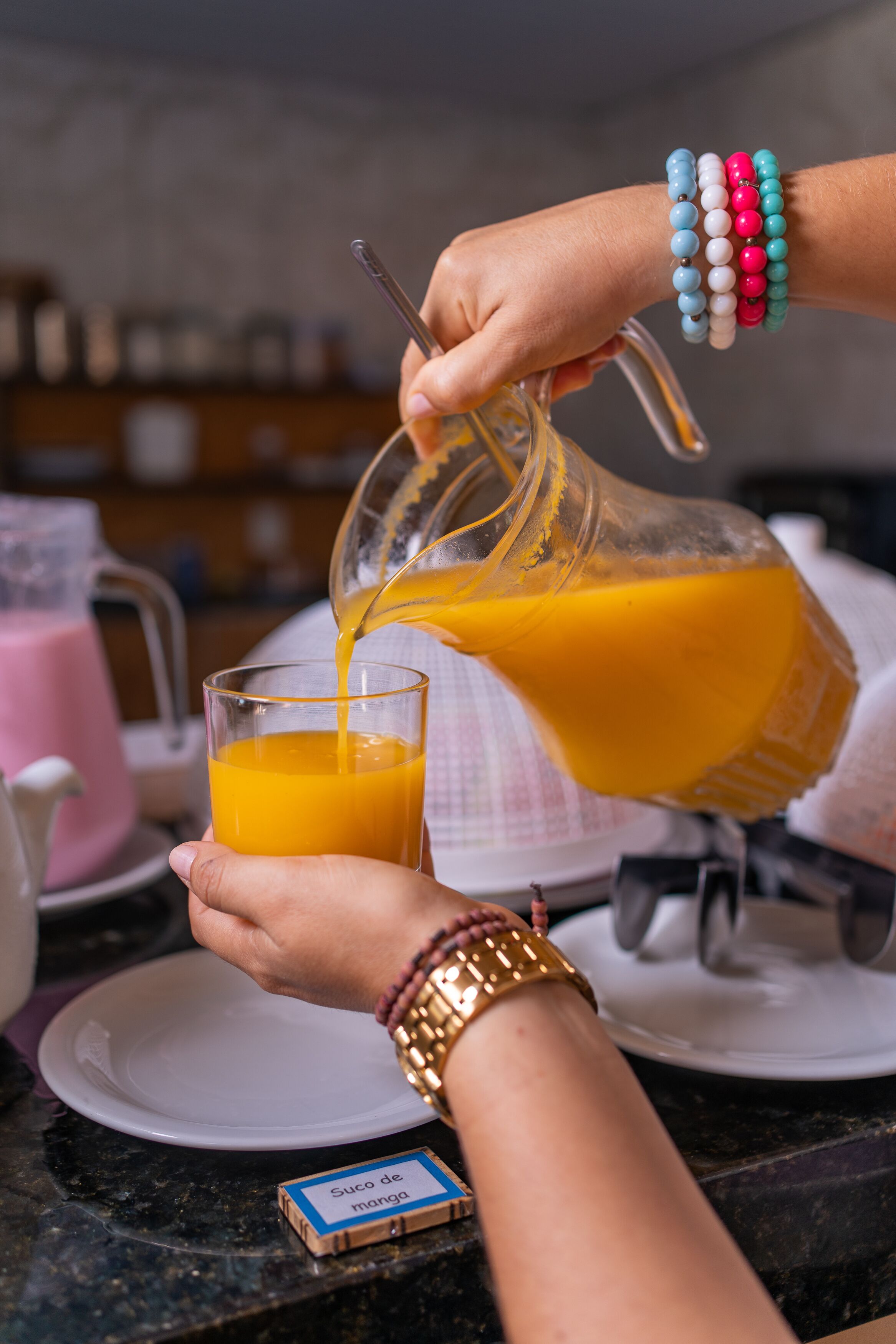 A person pouring orange juice into a glass.