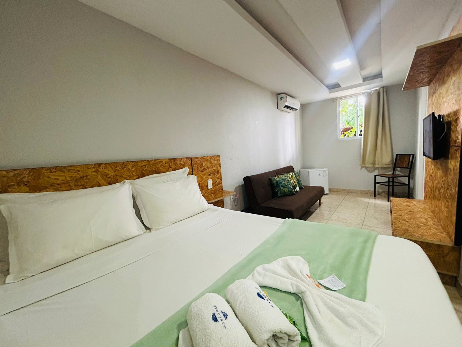 Una habitación de hotel con una cama, un sofá, un televisor y un equipo de aire acondicionado.