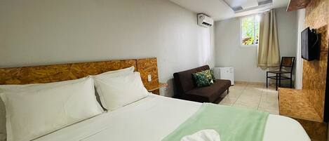 Una habitación de hotel con una cama, un sofá, un televisor y un equipo de aire acondicionado.